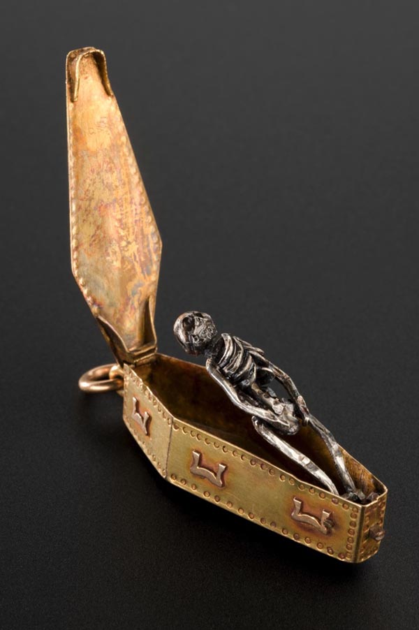 A coffin pendant opened to reveal a silver skeleton within.